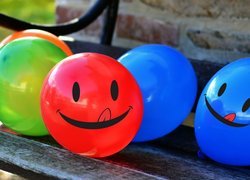 Kolorowe uśmiechnięte baloniki na ławce
