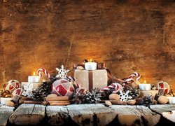 Kompozycja świąteczna z prezentami i świeczkami ułożona na deskach