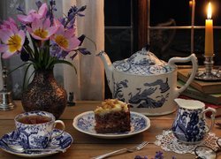 Kompozycja z filiżanką herbaty, ciastem i bukietem tulipanów w wazonie
