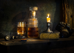 Kompozycja z karafką i aparatem w blasku świecy