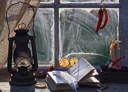 Kompozycja z lampą naftową i książką na oknie