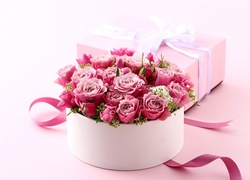 Kompozycja z różami w pudełku i prezentem przewiązanym wstążką
