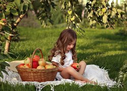 Kosz jabłek i dziewczynka na kocu