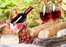 Kosz piknikowy z winem obok bagietki i winogron