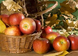 Koszyk z jabłkami i suche liście jesienne
