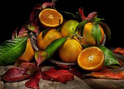 Koszyk z pomarańczami i kolorowymi liśćmi