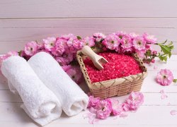 Koszyk z różową solą obok ręczników i gałązek migdałka