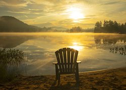 Krzesło na brzegu jeziora w blasku wschodzącego słońca