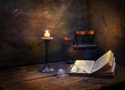 Książka i stare żelazko na stole w blasku palącej się świecy