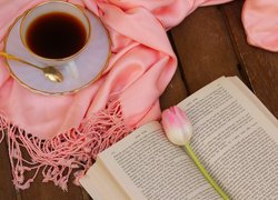 Książka i tulipan obok filiżanki kawy na szaliku