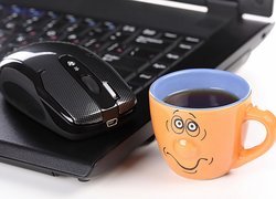 Kubek herbaty obok laptopa i myszki