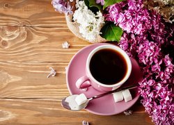 Kwiaty bzu położone obok filiżanki z kawą