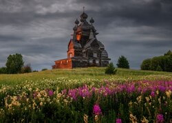 Kwiaty na łące i cerkiew w Żerebcowej Górze pod ciemnymi chmurami