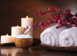 Kwiaty na ręcznikach obok soli kąpielowej i świec w SPA