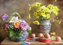 Kwiaty w koszyku i wazonie obok jajek