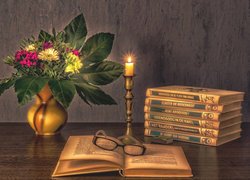 Kwiaty w wazonie i świeczka obok książek