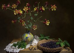 Kwiaty w wazonie obok koszyczka z owocami