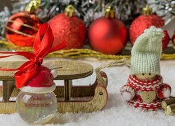 Laleczka w czapeczce obok sanek w dekoracji świątecznej