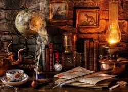 Lampa naftowa obok książek globusa i czajnika