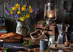 Lampa obok kwiatów w dzbanku babki i kawy w kubkach