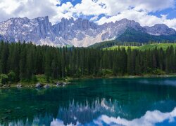 Las iglasty nad jeziorem i chmury nad Dolomitami