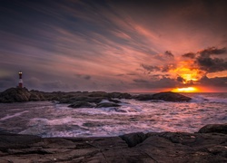 Latarnia morska na skałach o zachodzie słońca