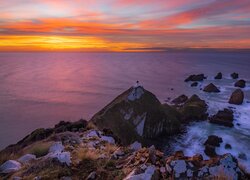 Latarnia morska Nugget Point na skale pod kolorowym niebem