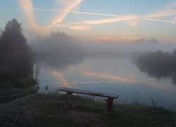 Ławka nad brzegiem zamglonego jeziora