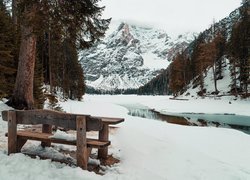 Ławka przy brzegu zaśnieżonego jeziora Pragser Wildsee