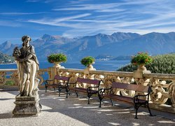 Ławki i posąg na tarasie nad jeziorem Lago di Como we Włoszech