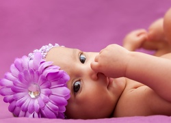 Leżące niemowlę w czapeczce z kwiatkiem