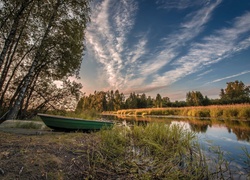 Łódka na brzegu rzeki pod jesiennymi drzewami