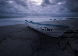 Łódka na plaży pod zachmurzonym niebem