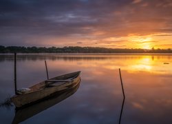 Łódka na tle zachodzącego słońca nad jeziorem