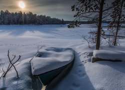 Łódka nad jeziorem zasypana śniegiem