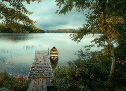 Łódka przy pomoście na brzegu jeziora