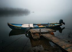 Łódka przy pomoście na zamglonym jeziorze