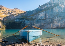 Łódka z wiosłami na brzegu górskiego jeziora