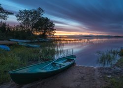 Łódki na brzegu jeziora o zachodzie słońca