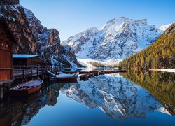 Łódki przy pomoście na jeziorze Lago di Braies w zimowych Dolomitach