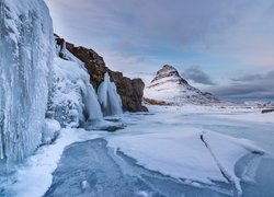 Lodowe sople na skale przy wodospadzie Kirkjufellsfoss w Islandii