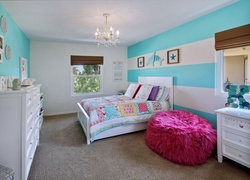 Łóżko nakryte patchworkową narzutą i różowy puf w niewielkiej sypialni