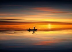 Ludzie na łódce w blasku zachodzącego słońca nad morzem
