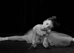 Mała baletnica z różą wykonująca szpagat