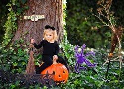 Mała czarownica z miotłą i dynią pod drzewem