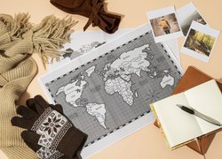 Mapa świata i notatnik obok rękawiczek i szalika