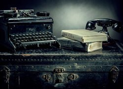 Maszyna do pisania, telefon i książki na starej walizce
