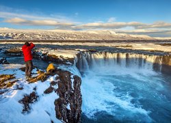 Mężczyzna fotografujący wodospad Godafoss