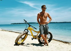Mężczyzna na plaży oparty o rower