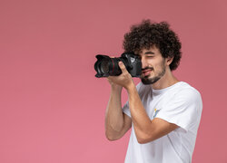 Mężczyzna w białej koszulce z aparatem fotograficznym